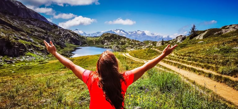 woman in red t-shirt standing on green grass field during daytime