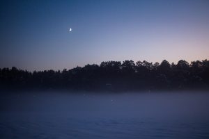 a foggy night with the moon in the distance