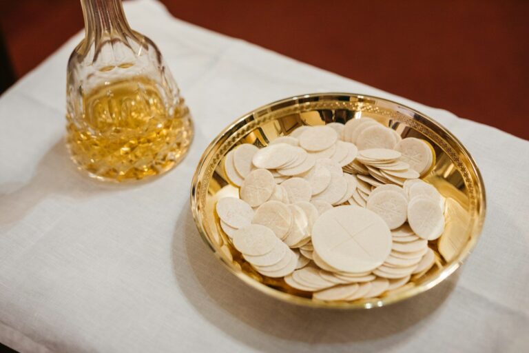 a gold bowl filled with coins next to a glass of wine
