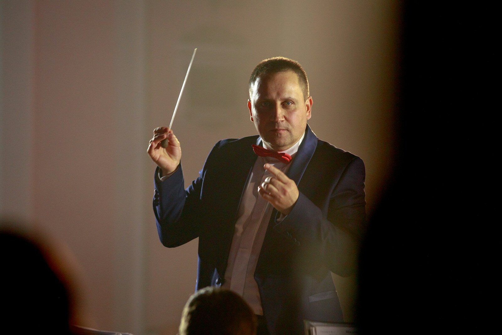 a man in a tuxedo holding a conductor's baton