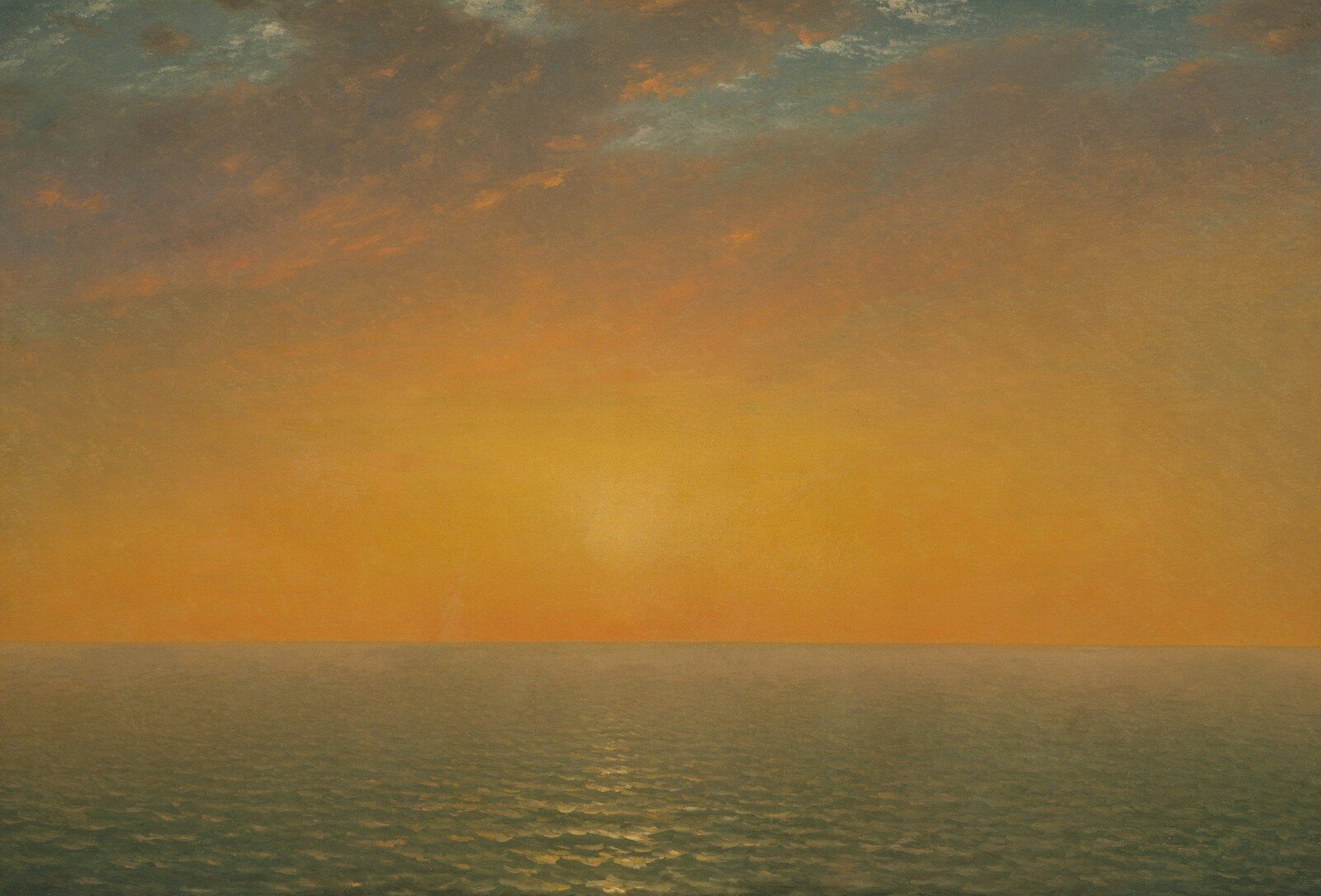 Low sun over a calm ocean under a warm orange sky
